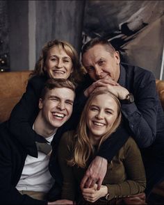 three people sitting on a couch with one person holding the other's head and smiling