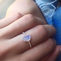 a woman's engagement ring with an opal stone in the center on her finger