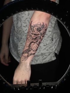 a person with a tattoo on their arm is standing in front of a circular mirror