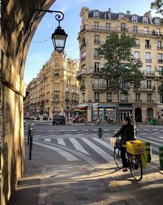 a person riding a bike down a street next to tall buildings