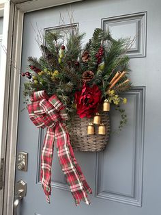 a basket filled with pine cones and evergreens hangs on the front door's handle