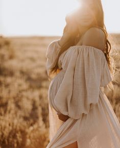 a woman in a white dress is walking through the field with her back to the camera