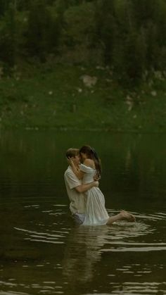 two people are in the water hugging each other and one person is wearing a white dress