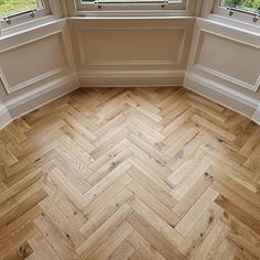 an empty room with two windows and wood flooring on the ground in front of them