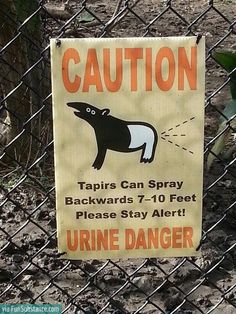 a caution sign posted on a chain link fence in front of an animal park enclosure