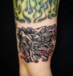 a man with a tattoo on his arm that has two wolf heads and flames in the background