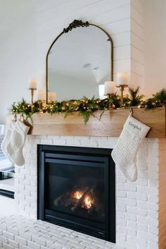 a fireplace with stockings hanging from the mantle and candles in front of it, decorated for christmas