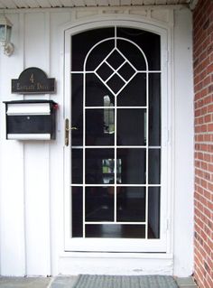 a white door with a glass window next to a brick wall and mailbox on the side