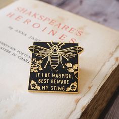 a black and gold bee pin sitting on top of an old book