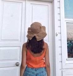 a woman standing in front of a white door with a hat on it's head