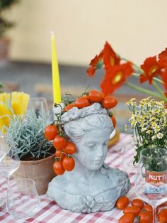 a small statue sitting on top of a table next to flowers and candles in vases