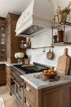 a kitchen with marble counter tops and wooden cabinets, along with an oven hood over the stove