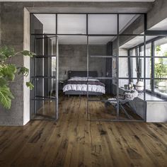 a bedroom with wooden floors and glass walls