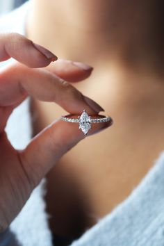 a woman's hand holding an engagement ring with a diamond on the middle finger