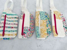 three pieces of fabric hanging from hooks on a wall with flowers and stripes in them