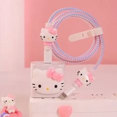 a hello kitty cell phone charger with pink and white accessories on top of it