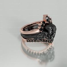 a black and white diamond ring set on top of a silver surface with an intricate design