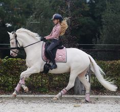 a woman riding on the back of a white horse