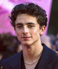 a close up of a person wearing a suit and tie with people in the background