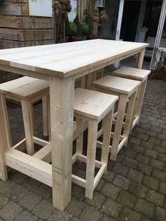 a wooden table with four stools sitting on top of it in front of a house