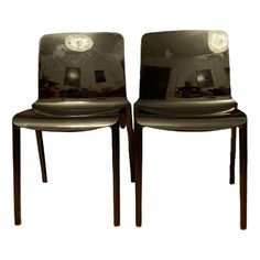 two chairs that are sitting side by side with the reflection of them in their backs