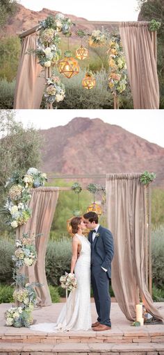 a couple kissing under an arch decorated with flowers and greenery for their wedding ceremony