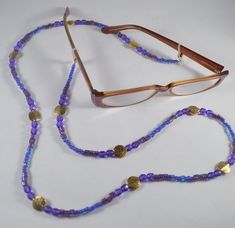 Beautiful 34" purple beaded eyeglass lanyard made with glass, pewter gold plated beads. Beads range from 4mm to 12mm and are various shapes including round, square and button. Rubber ends with gold ball to hold lanyard on glasses. This would make a lovely gift for a person who wears reading glasses and misplaces them often! Adjustable Gold Beaded Necklace With Oval Beads, Purple Glass Beaded Necklaces With Round Beads, Purple Glass Beaded Chain Jewelry, Adjustable Gold Nickel-free Beaded Necklace, Purple Glass Beaded Necklace With Round Beads, Adjustable Round Beaded Necklace With Gold Beads, Adjustable Gold Beaded Necklace With Czech Glass, Adjustable Gold Beaded Necklaces Nickel Free, Purple Glass Beaded Jewelry