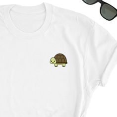 We have express delivery for our shirts! 📦⚡.  From cart to door in just 2-3 days, only for 3.5 USD extra.  You can find the express delivery option in the cart. Turtle Shirt, Cute Turtle Tee Shirt, Turtle Icon Tee Shirt, Turtle Lover T-Shirt, Turtle Cute Shirt Gift, Turtle Lover Friend UNISEX T-shirt Friends will love it! This t-shirt feels soft and lightweight, with the right amount of stretch. It's comfortable and flattering for both men and women.  * 100% cotton (heather colors contain polyester) * Fabric weight: 5 oz  * Shoulder-to-shoulder taping * Side-seamed Time for Delivery: * Processing & production time is 1-6 business days (usually 2-3 days). * U.S. Shipping time: 3-5 business days.  * International shipping time: 4-15 days. - Please note European customers: Some orders going Funny White Crew Neck Shirt, White Crew Neck Shirt With Funny Print, Clothes Dont Make The Turtle, Turtle Hoodie, Turtle T Shirt Design, Sea Turtle Tshirt Design, Turtle Shirts, Cute Turtles, Fun Sweatshirts