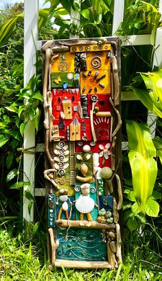 an art piece made out of various items in the grass with plants behind it and another object on the ground