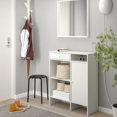 a room with a mirror, stool and coat rack on the wall next to a potted plant