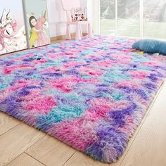 a pink, purple and blue area rug with unicorns on the wall behind it