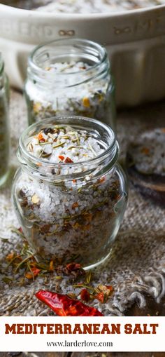 three glass jars filled with different types of salt and pepper on top of a table