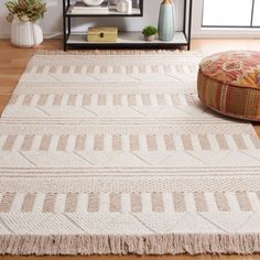 a white rug with fringes on the floor in front of a book shelf and window