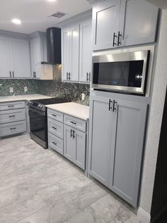 a kitchen with gray cabinets and white counter tops, stainless steel appliances and an oven