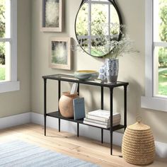 a table with books and vases on it in front of a wall mounted mirror