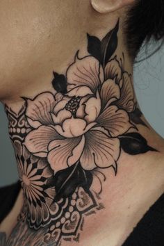 a woman with a black and white flower neck tattoo on her neck is looking at the camera