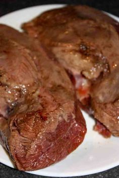 two pieces of steak on a white plate