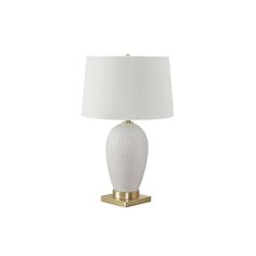 a white lamp with a gold base and a white shade on the top of it