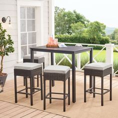 a table and four chairs on a porch with a potted tree in the background