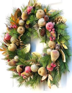 a christmas wreath with pine cones, berries and other holiday decorations hanging on a door