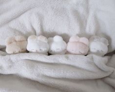 four stuffed animals are lined up in a row on a white bed linens covered by a blanket