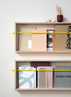 two shelves with books on each shelf and some writing on the wall behind them,