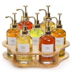 six soap dispensers with labels on them sitting on a wooden tray in front of a white background