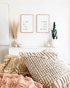 two framed pictures on the wall above a bed with pink and white sheets, pillows and blankets