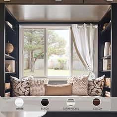 the inside of a window seat in a living room with white curtains and brown pillows