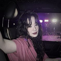 a woman sitting in the passenger seat of a car with her hand on the steering wheel