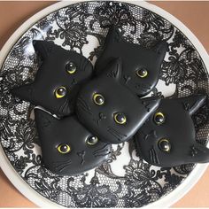 three black cats are sitting on a plate