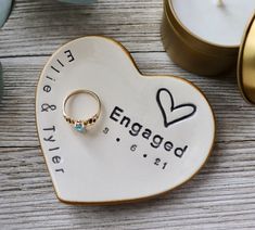 an engagement ring sits on top of a heart shaped plate next to candles and a candle holder