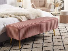 a bed with a pink bench on top of it in front of a white rug