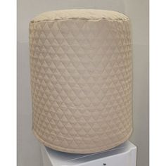 a large beige quilted lamp shade sitting on top of a white light switch box